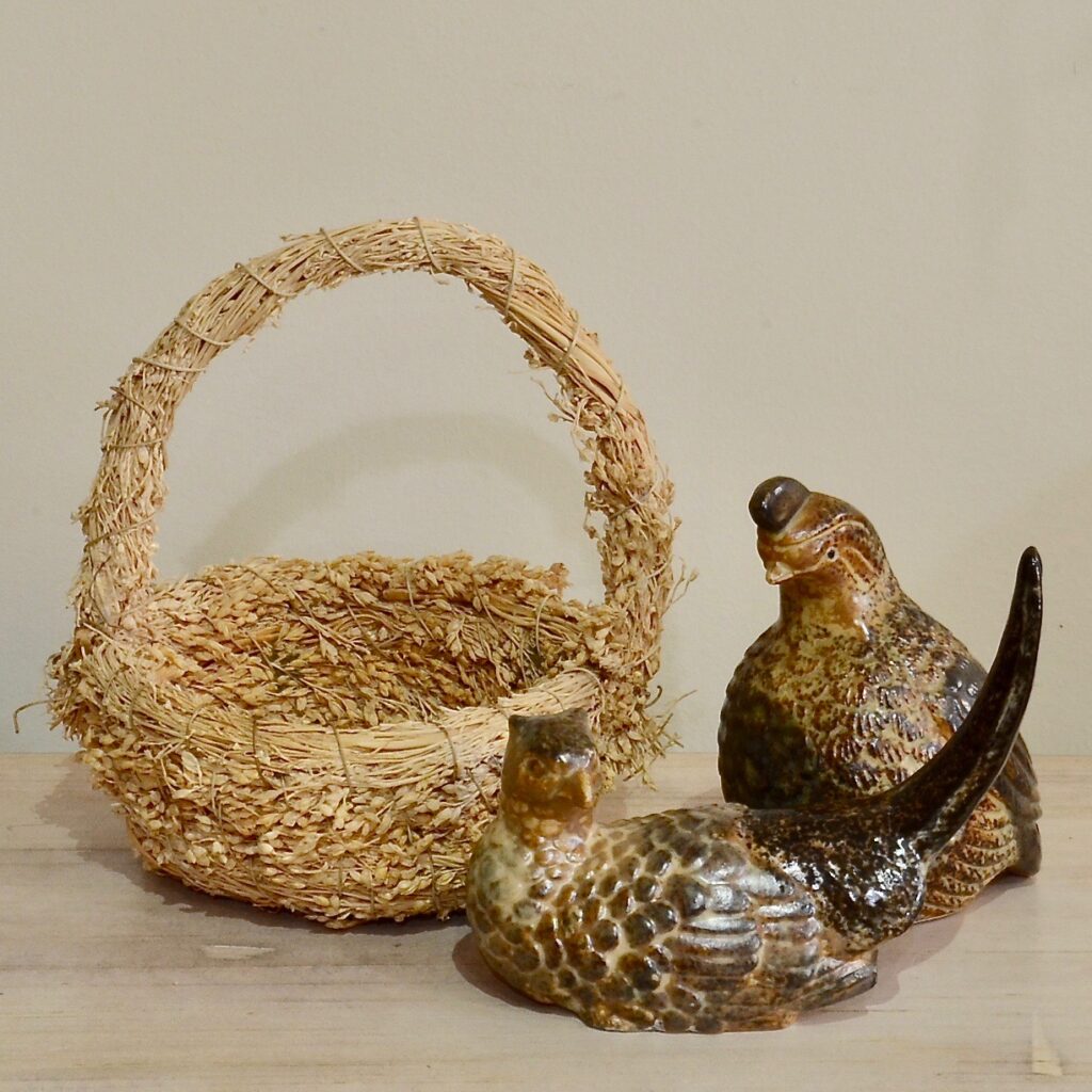 grass basket with two wildlife figures, one pheasant and one quail